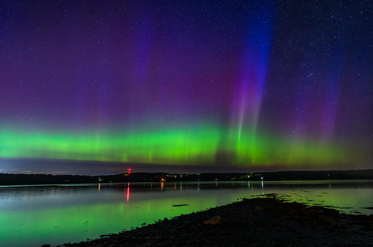 The Aurora shines over the tidal flats of Bar Harbor, Maine, with rare blue rays pulsating