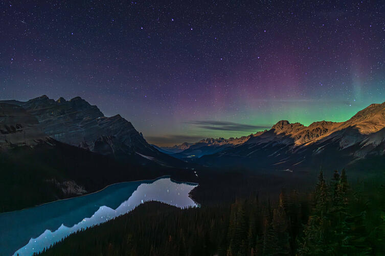Aurora makes an appearance over Banff National Park in Alberta, Canada, hovering over the milky waters of Peyto Lake